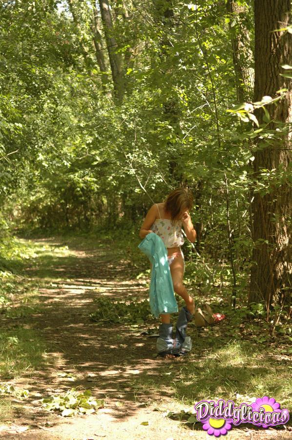 L'adolescente bruna diddy si prende in giro con la sua canottiera rosa e i suoi jeans nel bosco
 #54054003