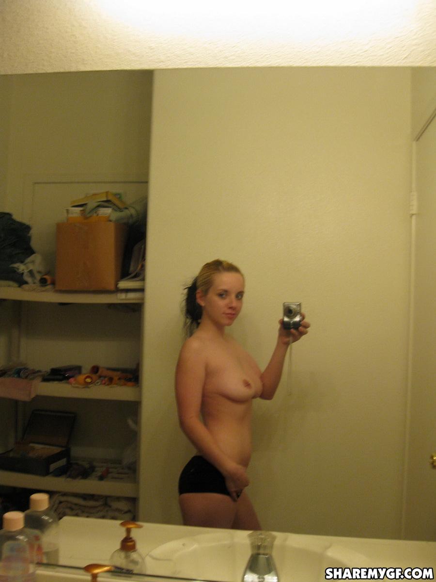 かわいいブロンドの彼女が裸になって、ピアスをした乳首を鏡に映して自撮りする
 #60791312