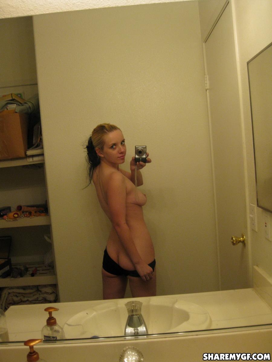 かわいいブロンドの彼女が裸になって、ピアスをした乳首を鏡に映して自撮りする
 #60791328