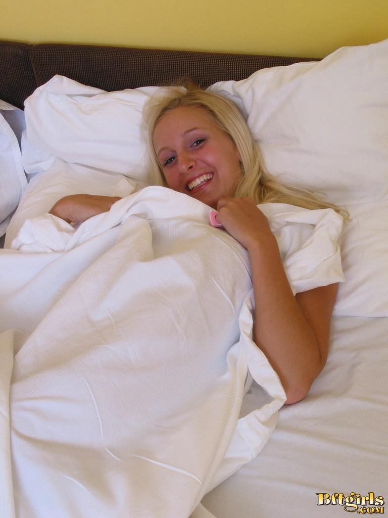Une belle jeune blonde se déshabille au lit et joue avec ses orteils
 #60257058
