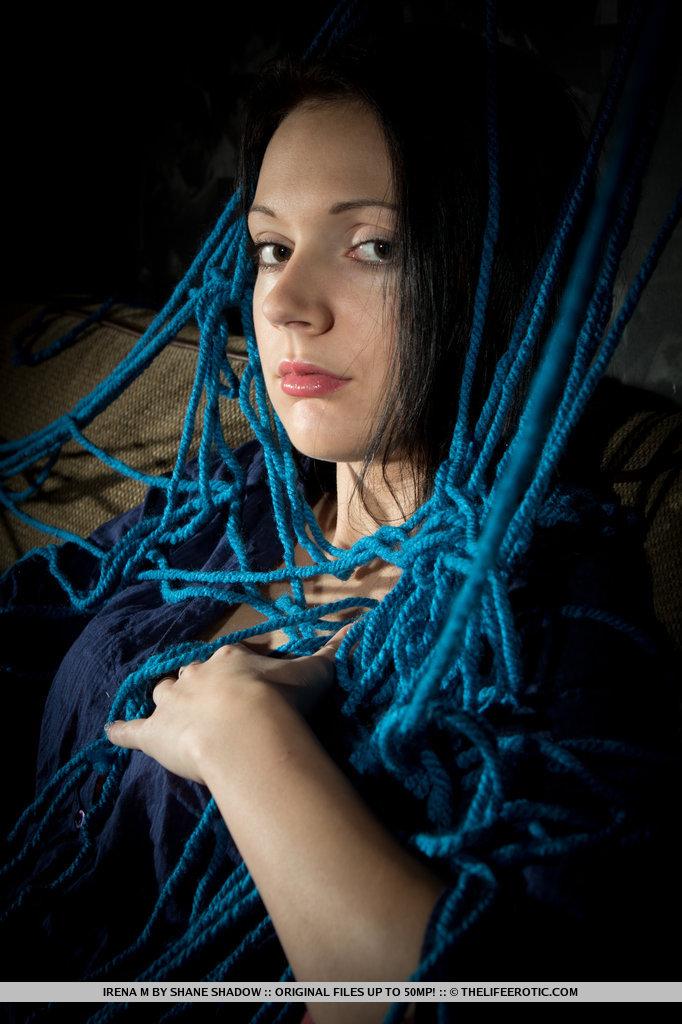 Un enchevêtrement de cordes bleues enveloppe le corps d'Irène qui se masturbe sur le canapé rembourré.
 #54903482