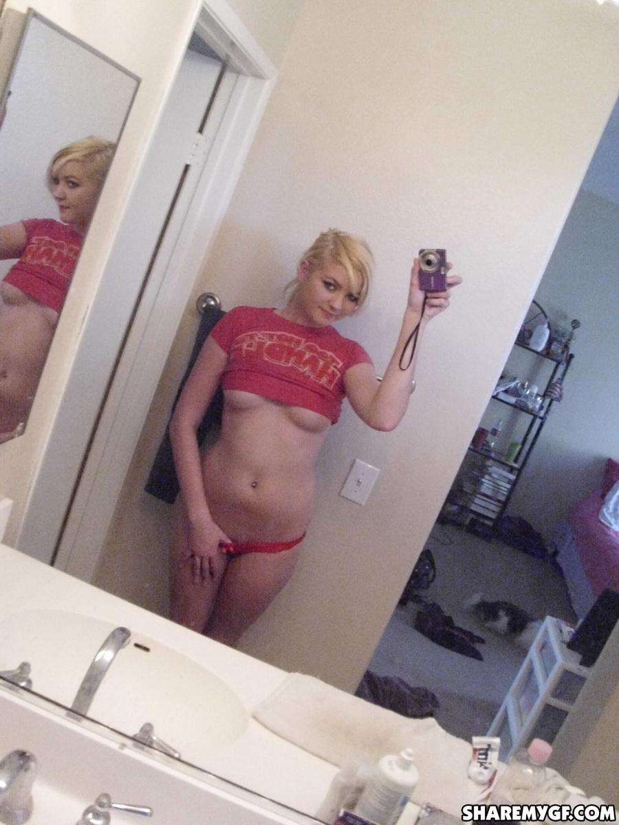 Une jeune femme blonde prend des selfies de son superbe corps dans la salle de bain.
 #60795675