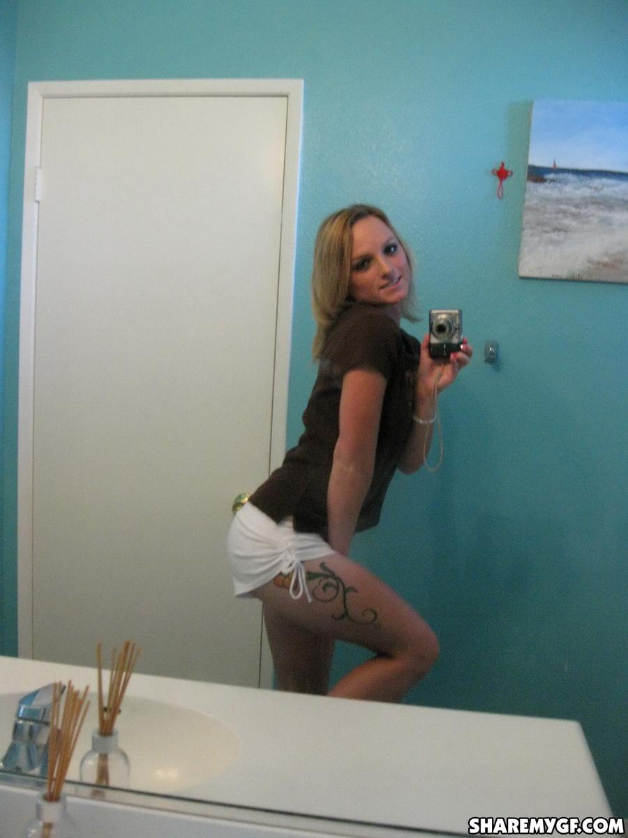 Une jeune femme blonde sexy prend des selfies de son corps nu dans la salle de bain.
 #60796297