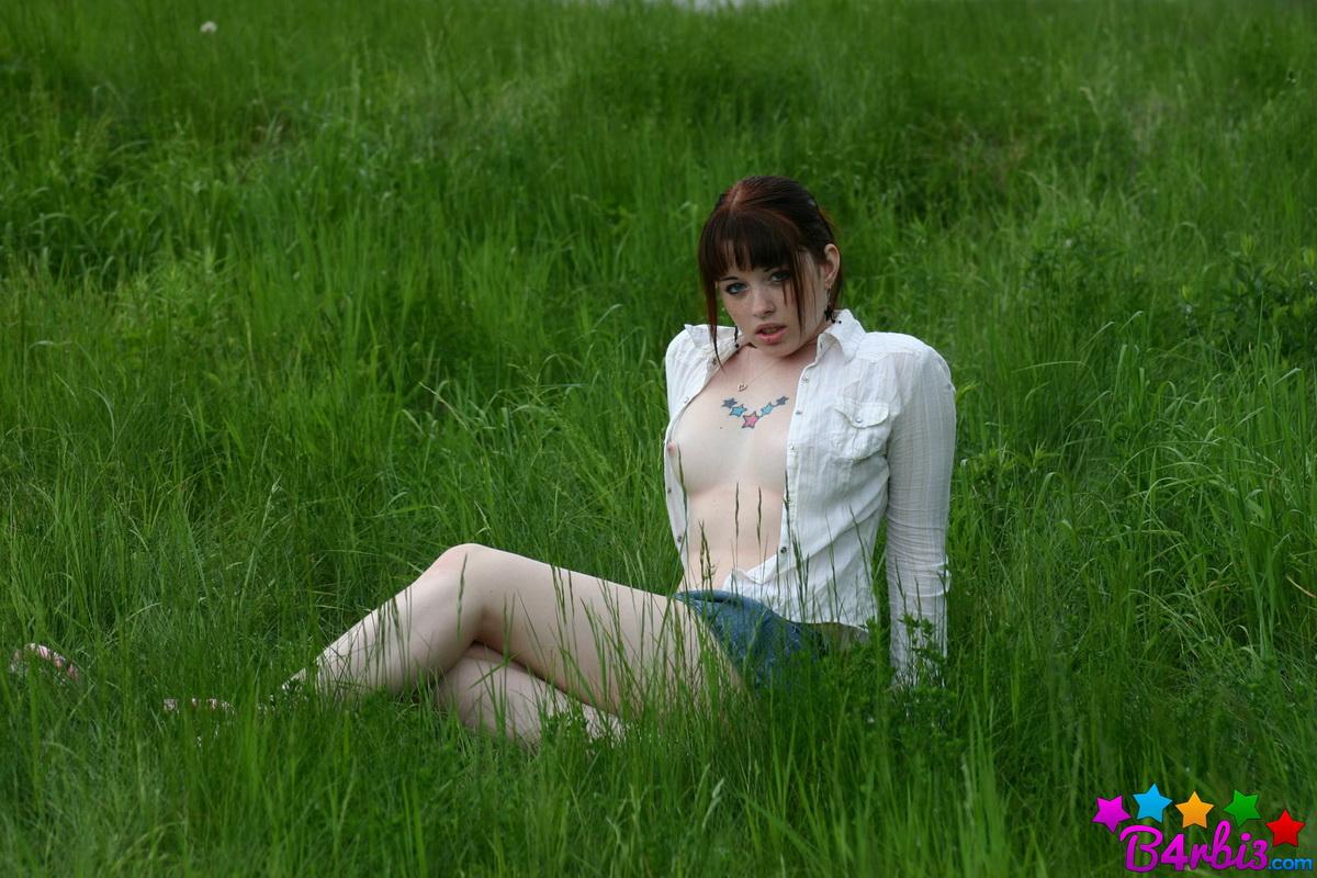 Barbie zeigt ihre frechen Brüste, als sie ihr Oberteil draußen im Grasfeld aufknöpft
 #53414803