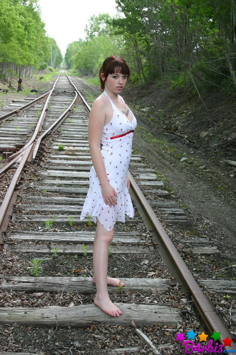 Barbie neckt, wie sie auf den Bahngleisen in einem knappen Sommerkleid posiert
 #53414231