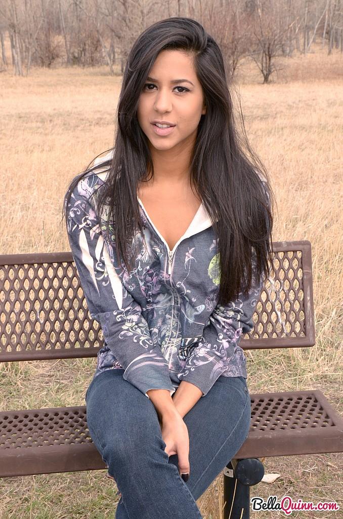 Bella Quinn, una joven morena, posa en un banco al aire libre
 #53431848