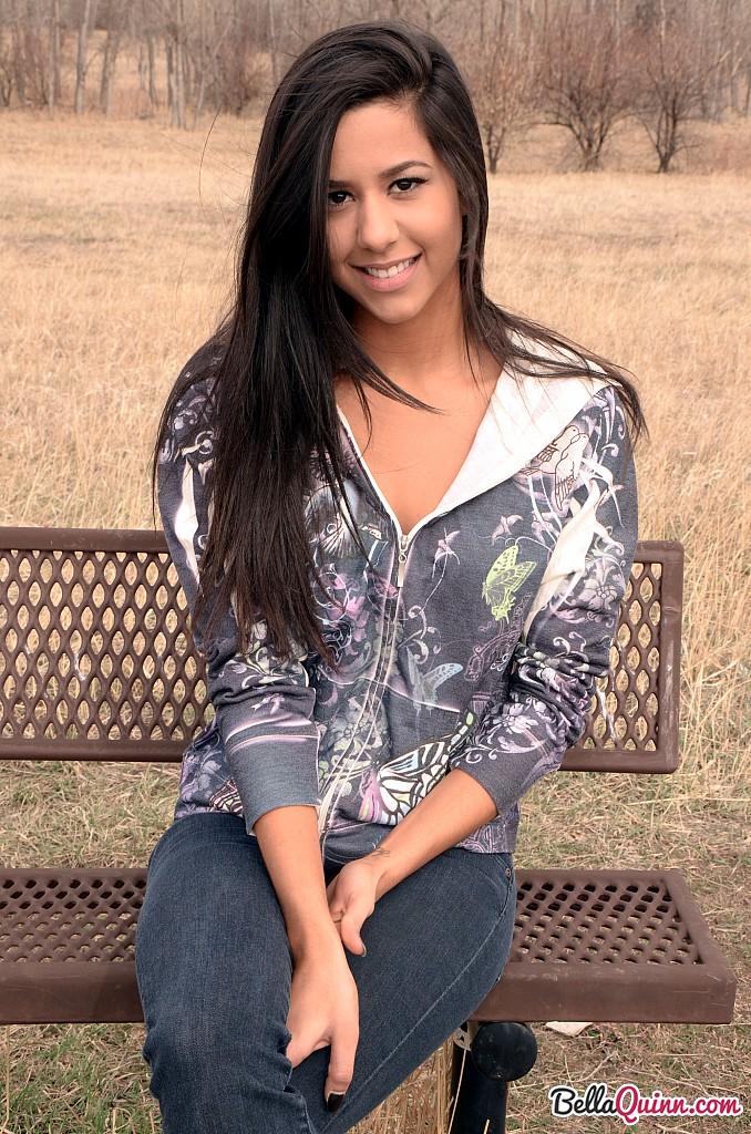 Bella Quinn, una joven morena, posa en un banco al aire libre
 #53431886