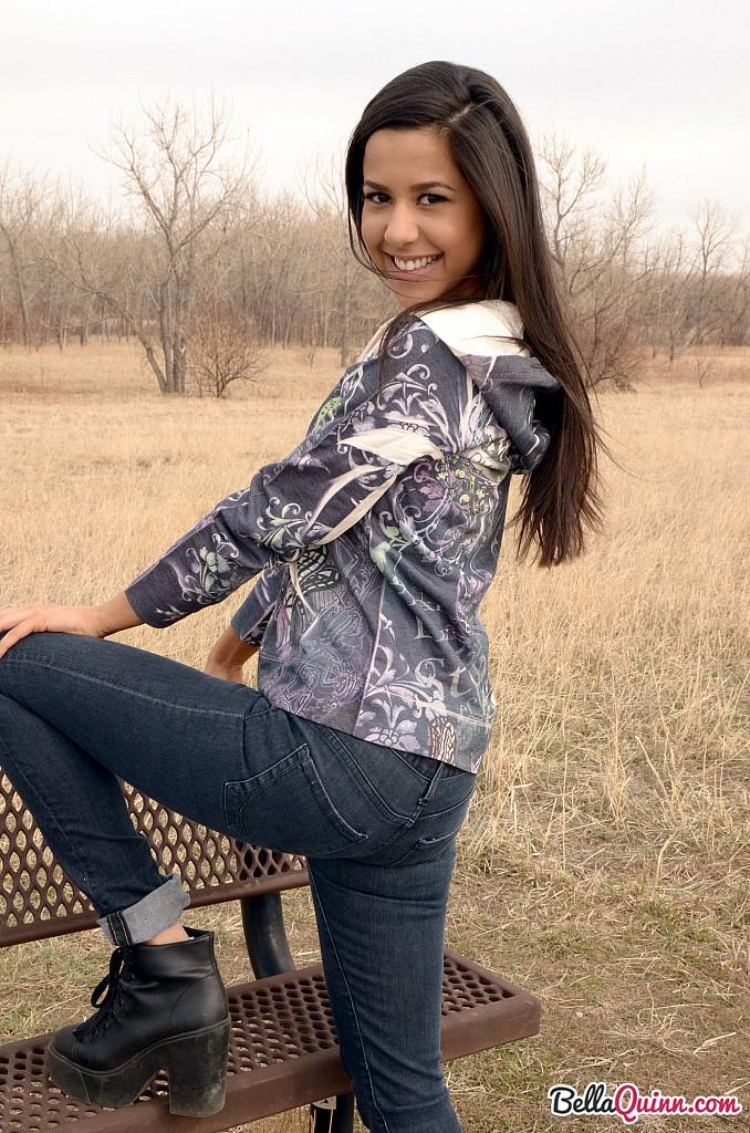 Bella Quinn, una joven morena, posa en un banco al aire libre
 #53431950