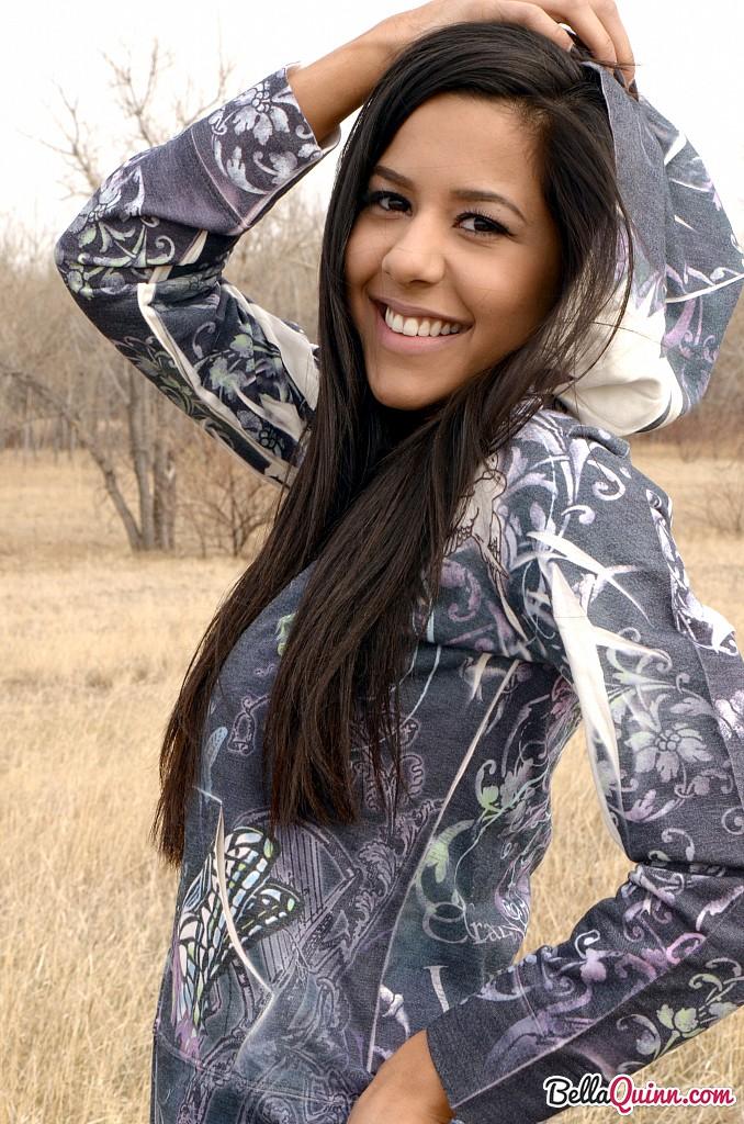 Bella Quinn, una joven morena, posa en un banco al aire libre
 #53431969