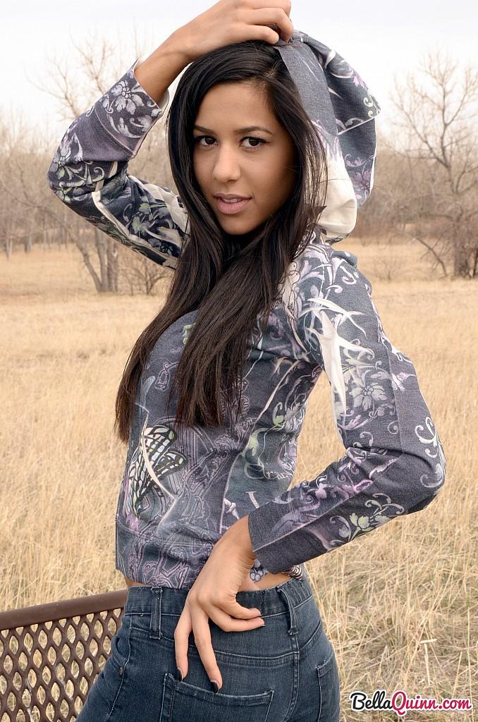 Bella Quinn, una joven morena, posa en un banco al aire libre
 #53431991