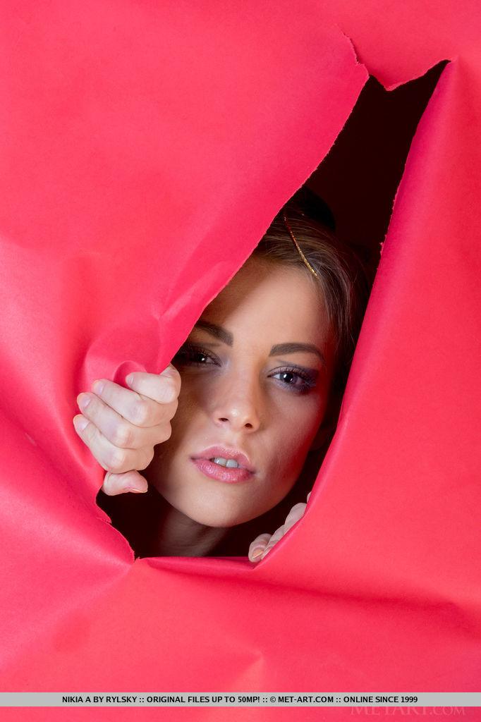 Un servizio fotografico artistico con nikia a che posa nuda contro una carta da parati strappata rossa brillante
 #59771012