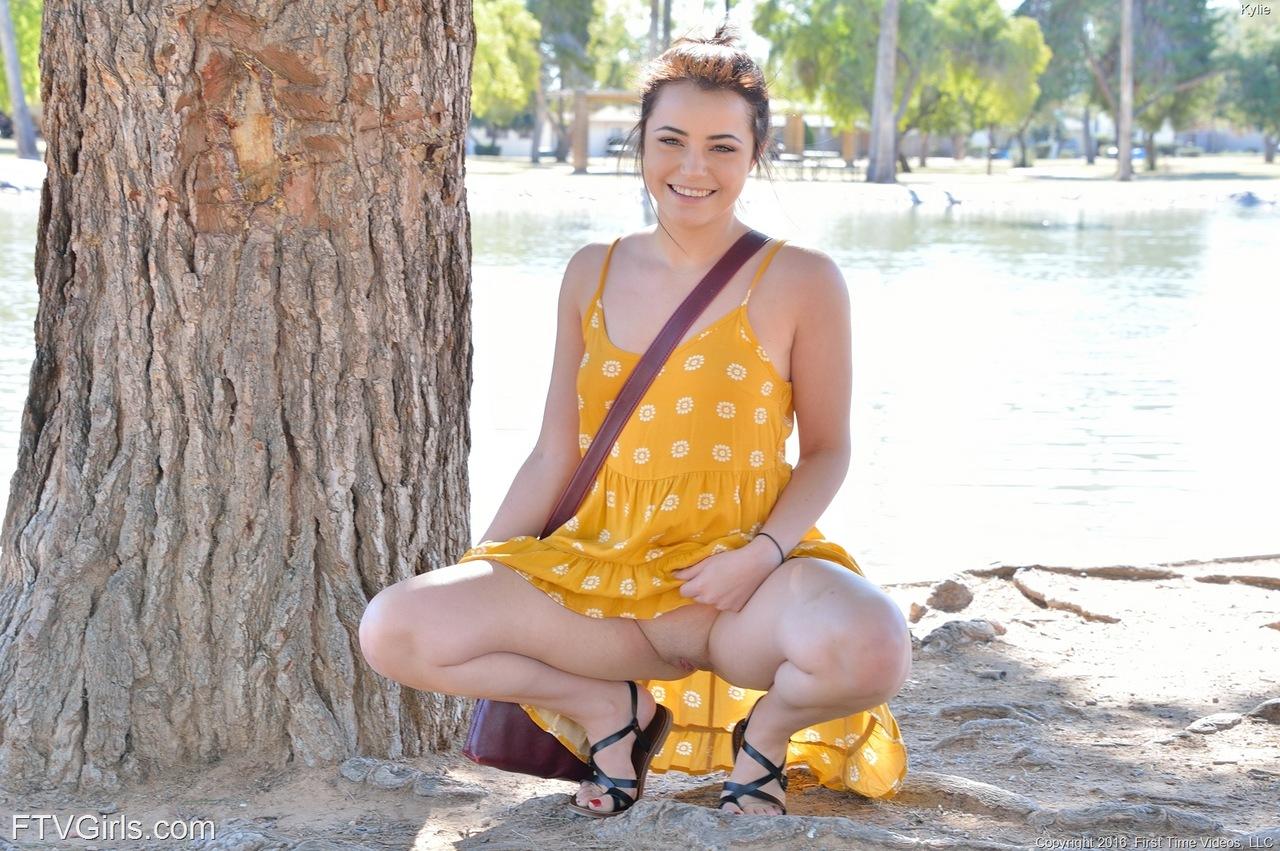 Kylie, jeune femme sexy, soulève sa robe jaune pour vous montrer sa chatte dans un parc public.
 #58785914