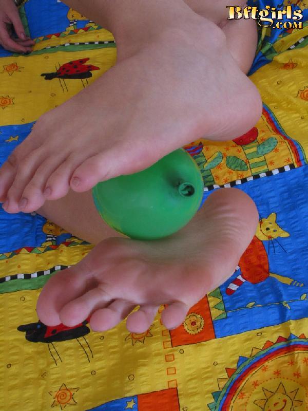 Una linda joven morena usa sus pies para jugar con un globo
 #60254527